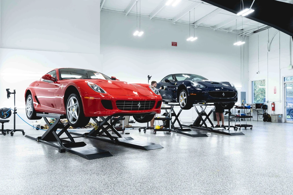 Two Ferraris on lifts inside the Detailers of Naples climate-controlled bay