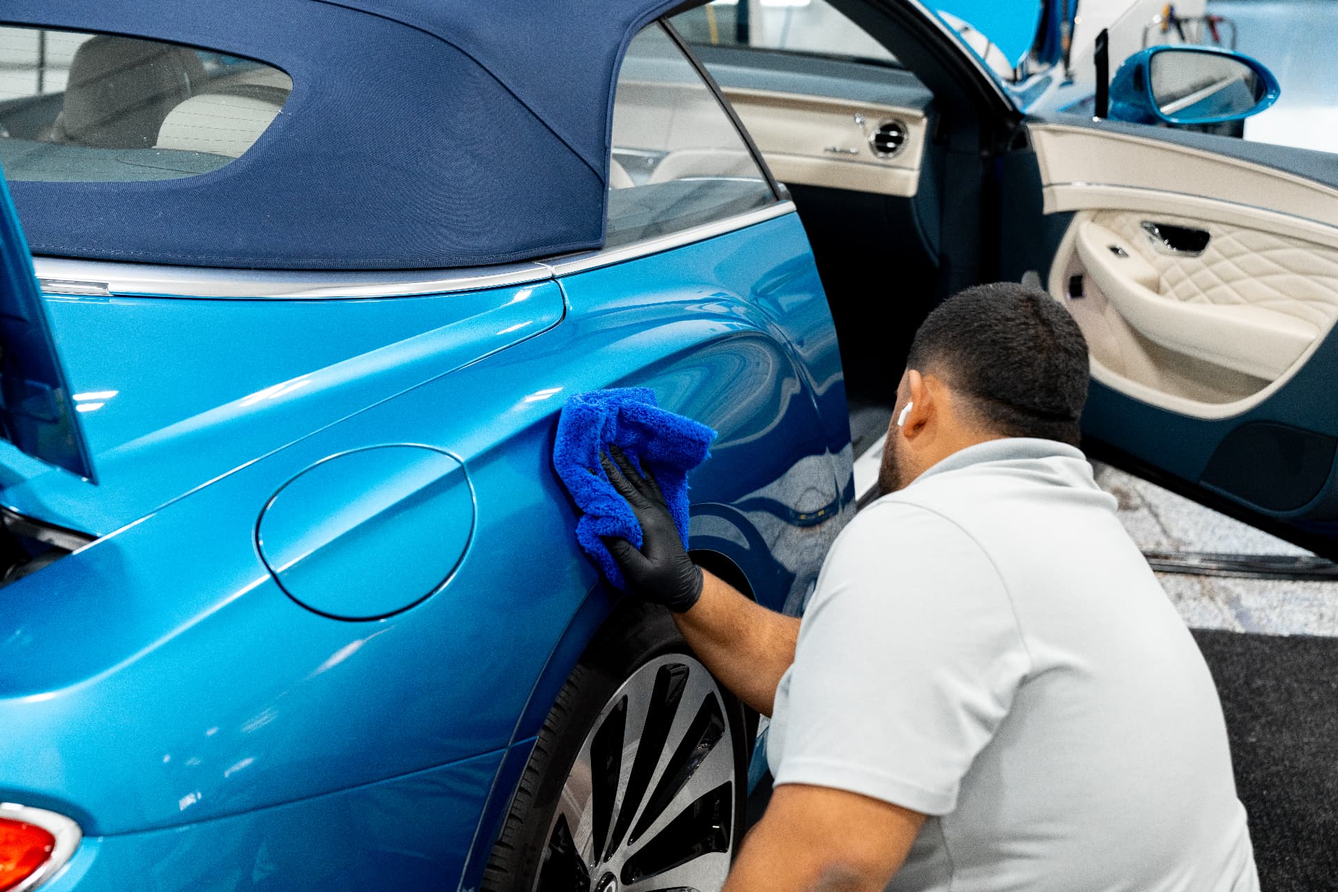 Detailers of Naples technician carefully finishing a blue convertible in the installation bay